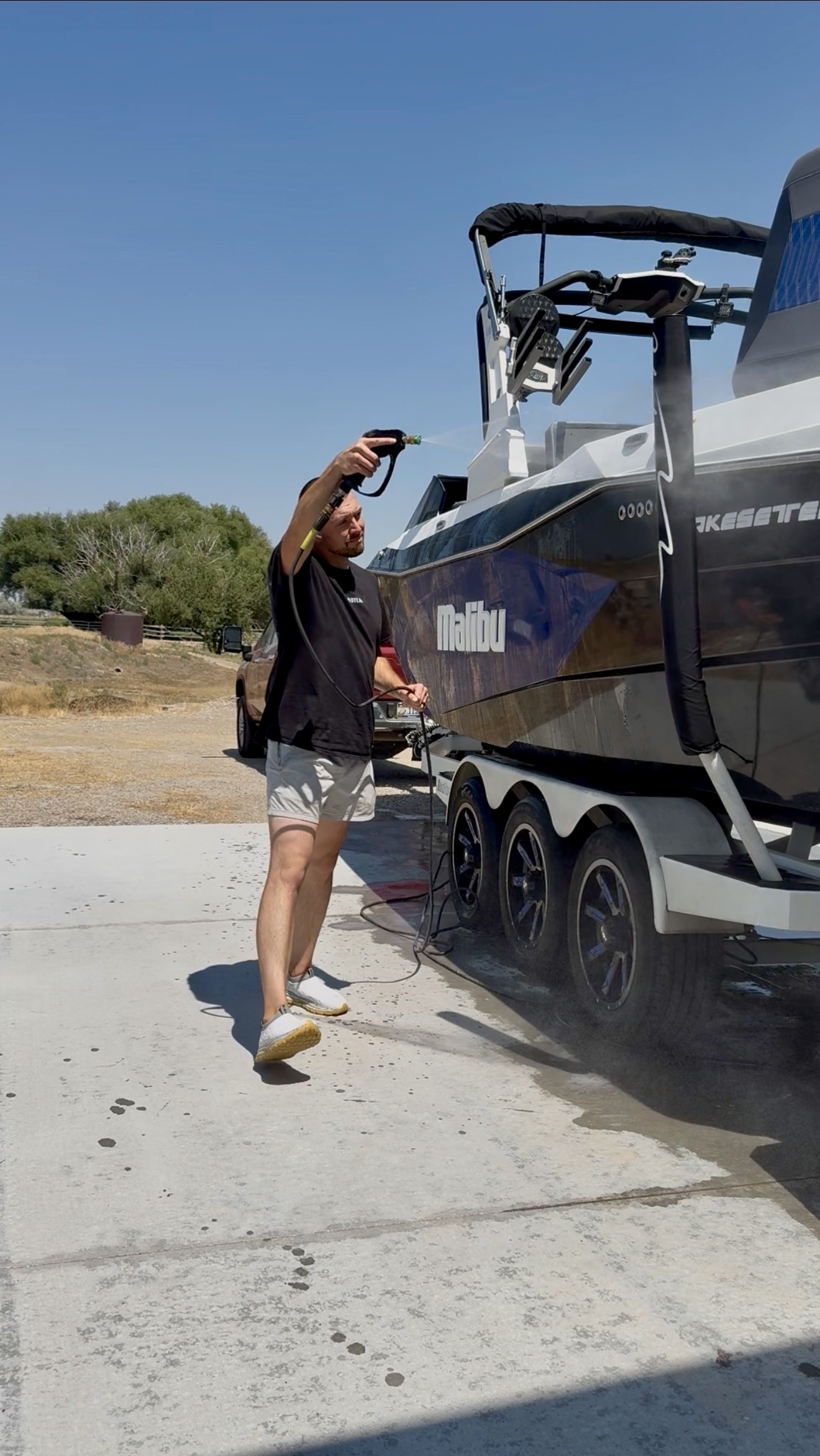 PRO DTLR detailer pressure-washing a Malibu wakeboard boat on its trailer