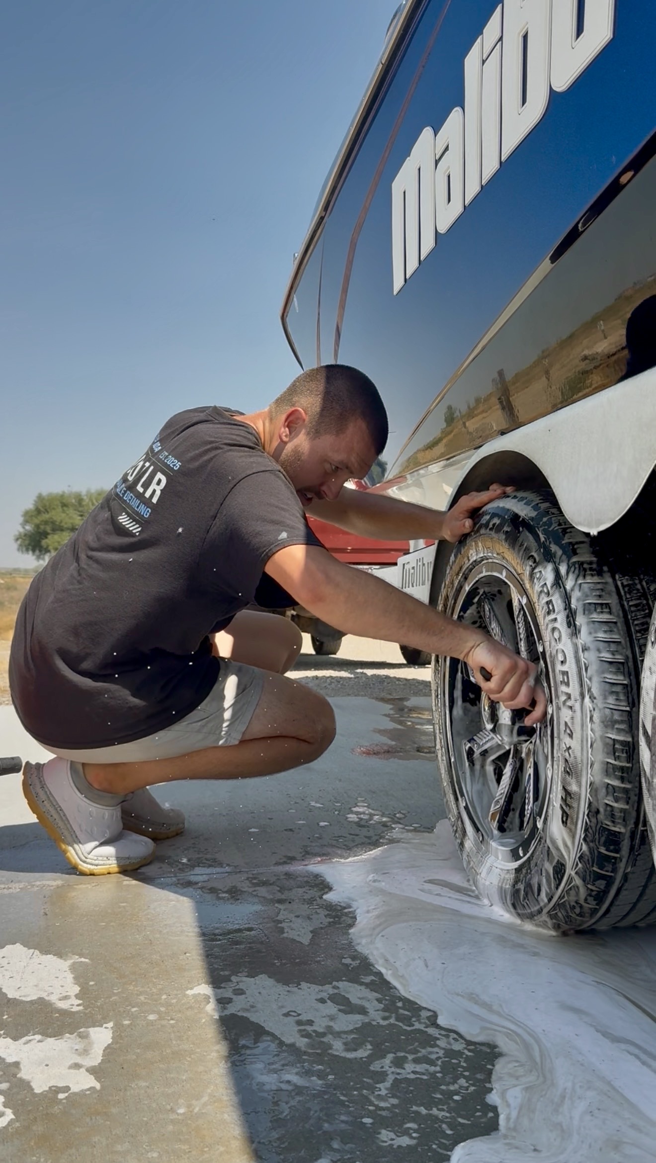 PRO DTLR detailer scrubbing a boat trailer wheel on-site at a customer's location
