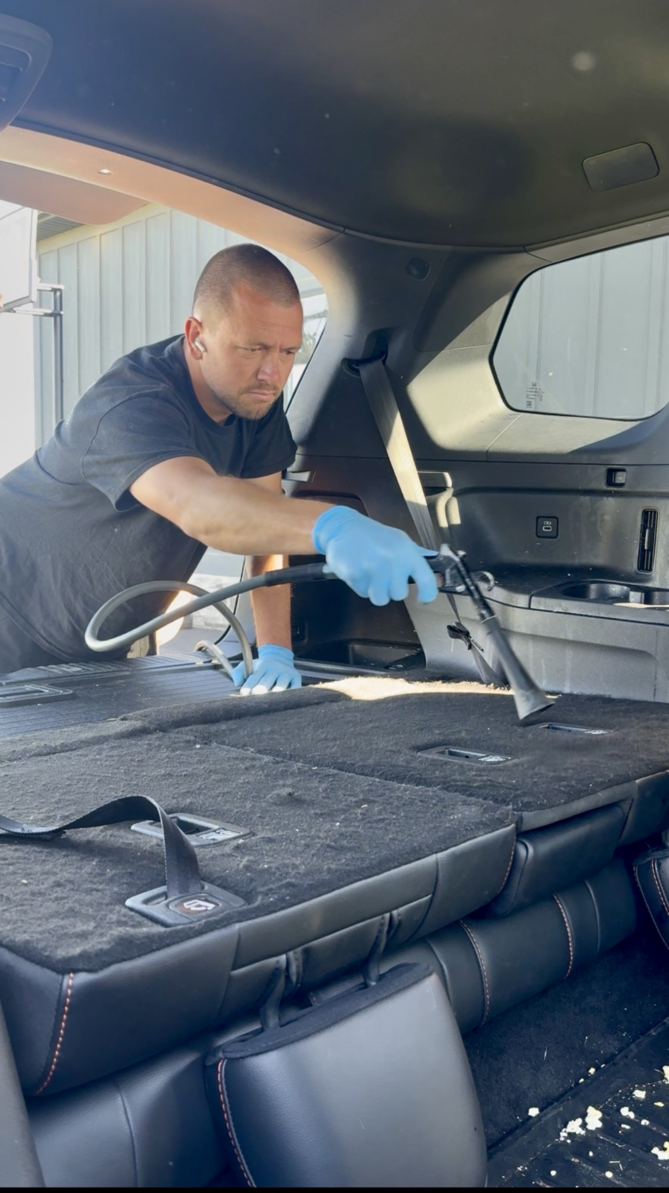 PRO DTLR detailer extracting and vacuuming an SUV cargo area during an interior detail
