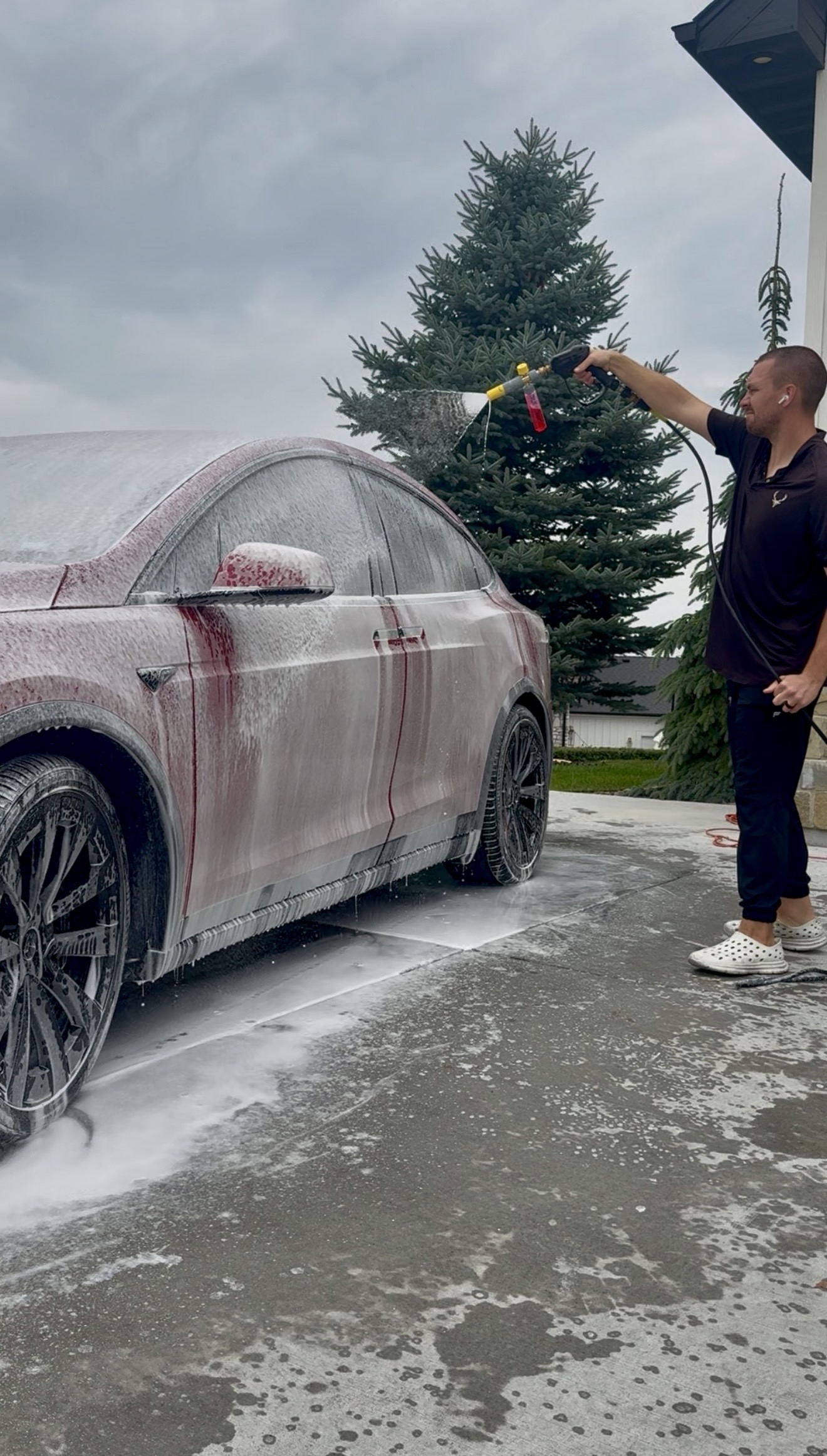 PRO DTLR detailer foam-washing a red Tesla in a customer's driveway